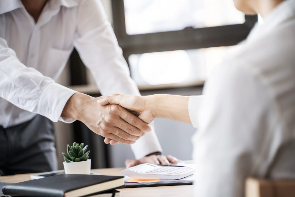 business executives shaking hands after meeting at office, colle