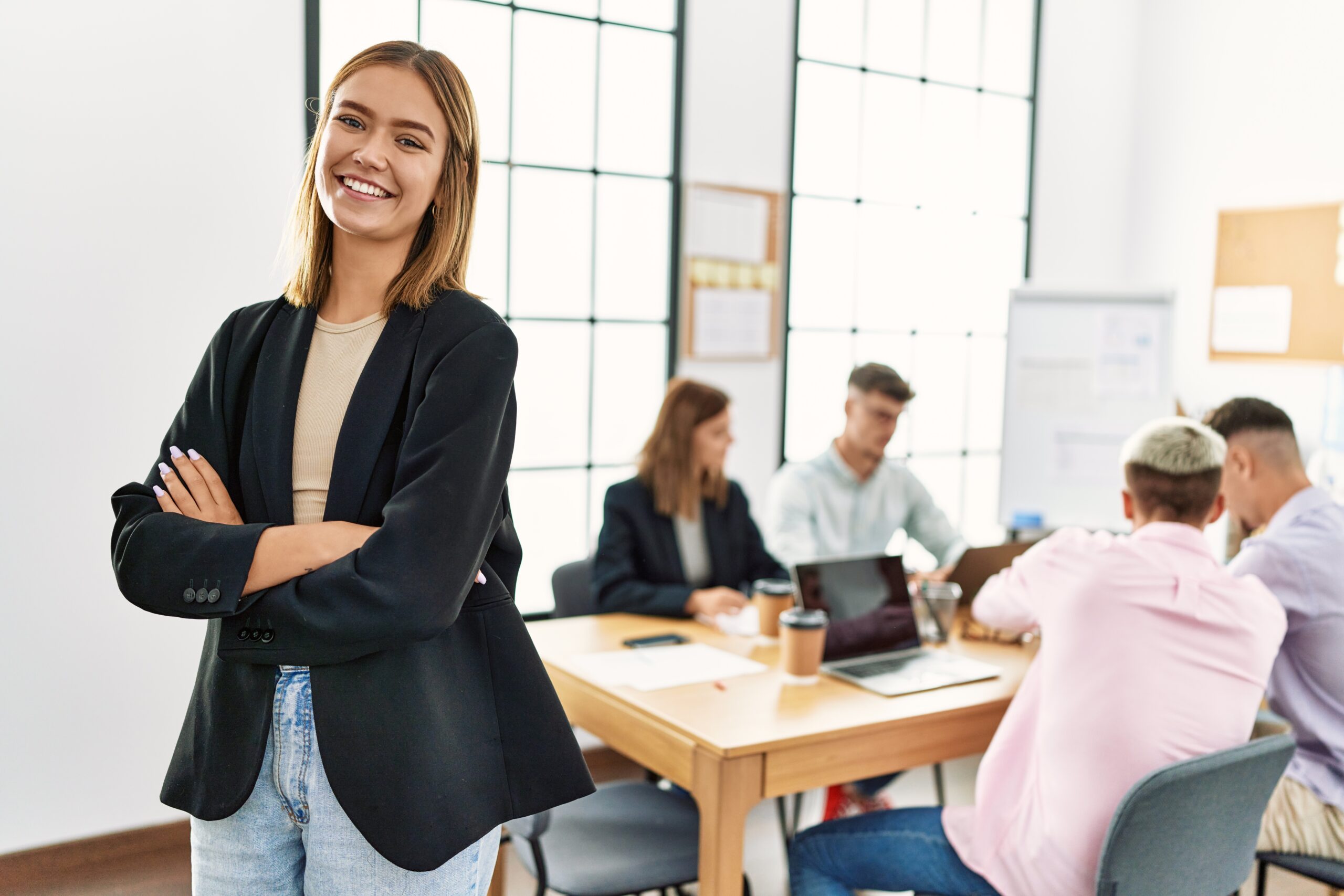young hispanic businesswoman smiling happy standing with arms crossed gesture at the office during business meeting.